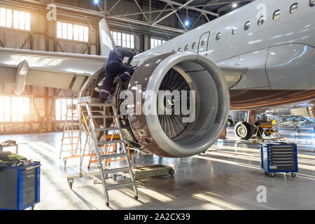 Specialista meccanico ripara la manutenzione del motore di un aereo passeggeri in un hangar. Foto Stock