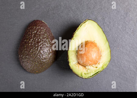 Esotici avocado fresco su nero ardesia con spazio di copia Foto Stock