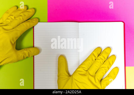 Punto coperta da un guanto dito ad un magazzino vuoto pagina. Rosa luminoso e sfondo giallo. Foto Stock