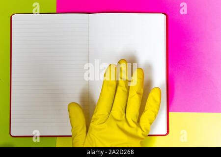 Punto coperta da un guanto dito ad un magazzino vuoto pagina. Rosa luminoso e sfondo giallo. Foto Stock