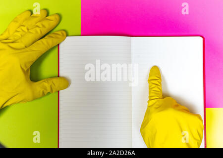 Punto coperta da un guanto dito ad un magazzino vuoto pagina. Rosa luminoso e sfondo giallo. Foto Stock