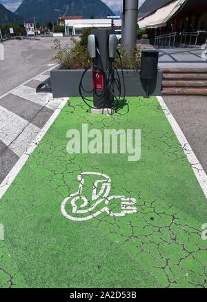 Il veicolo elettrico (VE) stazione di carica posto parcheggio con icona testo su invecchiamento dipinte di verde marciapiede. Foto Stock