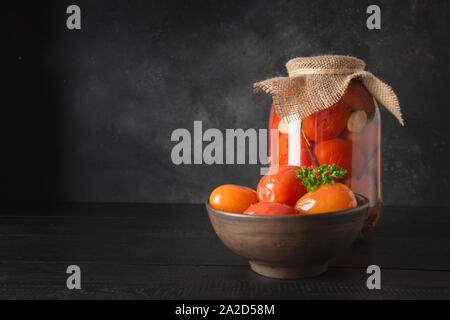 In casa sour pomodori marinati. Conserve di verdure in vasi di vetro sulla tavola di legno. Spazio per il testo. Foto Stock