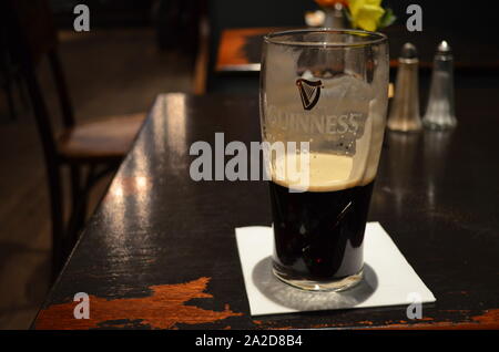 Quasi vuoto pinta di Guinness seduto su una tabella pub in Glasgow Foto Stock