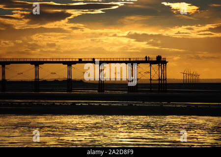 Tramonto sul mare del Nord con sagome di turbine eoliche e un molo, Saltburn, North Yorkshire, Inghilterra, Regno Unito. Foto Stock