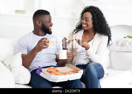 Felice coppia millenario di mangiare pizza e bere il caffè a casa Foto Stock