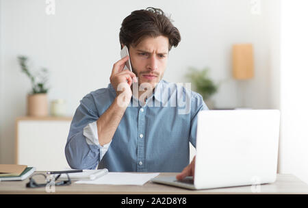 Imprenditore parlando al telefono cellulare seduti al posto di lavoro Foto Stock