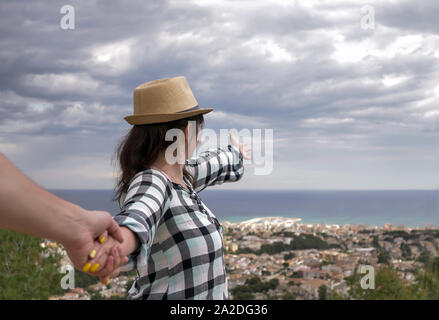 Turista tiene una mano d'uomo e punti in avanti. follow me Foto Stock