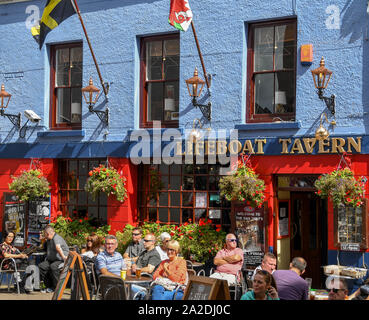 TENBY, Pembrokeshire, Galles - Agosto 2018: Gente seduta al di fuori della scialuppa di salvataggio taverna casa pubblica nel centro della cittadina di Tenby, West Wales, su un summe Foto Stock