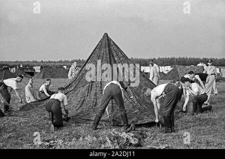 Rekruten der Luftwaffe der Wehrmacht bauen im Rahmen der militärischen Grundausbildung ein Zelt auf, Deutschland 1930er Jahre. Reclute della Luftwaffe tedesca portando una tenda nella loro formazione militare, Germania 1930s. Foto Stock