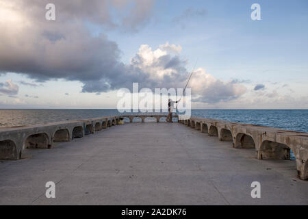 L'uomo getta la linea della canna da pesca in mare in Olinda pier Foto Stock