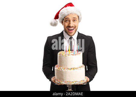 Eccitato giovane in un abito indossando un cappello di Natale e tenendo una torta isolati su sfondo bianco Foto Stock