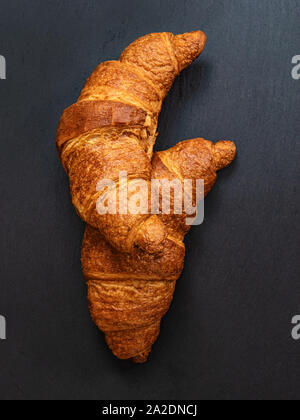 I croissant su grigio scuro dello sfondo in ardesia. Minimal design concept. Foto Stock