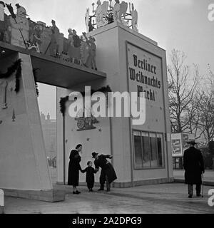 Ein kleiner Junge mit seinen Eltern am Eingang zum Berliner Weihnachtsmarkt, Deutschland 1930er Jahre. Un ragazzino con i suoi genitori all'ingresso della Berlino Mercatini di Natale, Germania 1930s. Foto Stock