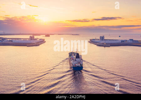 Cisterna di carico con prodotti petroliferi vele nel porto di una città industriale porta all'alba al mattino, vista aerea Foto Stock