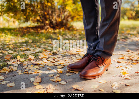 Imprenditore indossando scarpe in autunno park. In pelle marrone calzature classiche. Close up di gambe Foto Stock