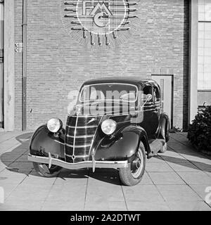Ford V8 vor der Firmenzentrale der Ford Werke in Köln Niehl, Deutschland 1930er Jahre. Una Ford V8 nella parte anteriore del tedesco Ford sede a Colonia, Germania 1930s. Foto Stock