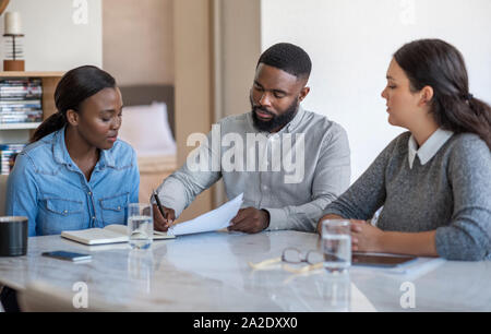 African American giovane firma di documenti con la loro pianificatore finanziario Foto Stock