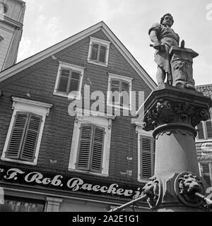 Denkmal des tapferen Schmieds Peter Hahn vor dem Modehaus Baecker auf dem Alten Markt in Solingen, Deutschland 1930er Jahre. Monumento del brave fabbro Peter Hahn nella parte anteriore del negozio di moda Baecker presso il vecchio mercato principale a Solingen, Germania 1930s. Foto Stock