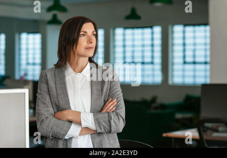 Imprenditrice nel profondo pensiero mentre in piedi dalla sua scrivania da ufficio Foto Stock
