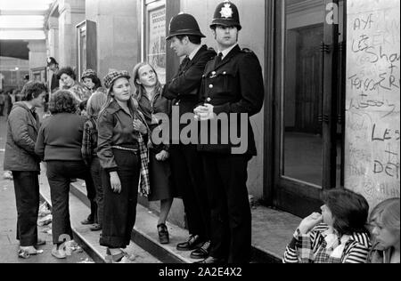 1970 UK Teenage girl Bay City Roller tifosi. Il gruppo di musica pop Boy band lascia il concerto pop ad Hammersmith Odeon, West London 1975. Le ragazze indossano la moda tartan Bay City Roller, chiacchierando con i poliziotti che sono lì per tenere ordine! 70 HOMER SYKES Foto Stock