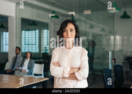 Giovane imprenditrice in piedi con fiducia in un grande ufficio moderno Foto Stock