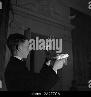Ein Lehrjunge in einem Ristorante bringt die Gläser auf Hochglanz im Reichsberufswettkampf 1937, Deutschland 1930er Jahre. Un partecipante di un ristorante la lucidatura di bicchieri al concorso Reichsberufswettkampf 1937, Germania 1930s. Foto Stock