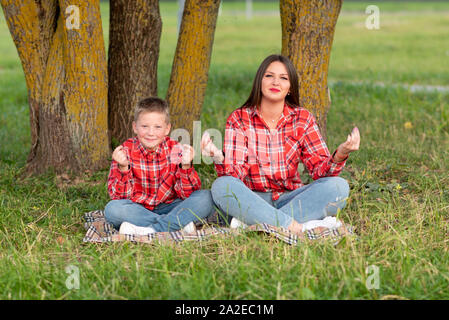 La mamma insegna a suo figlio yoga nella natura. Foto Stock