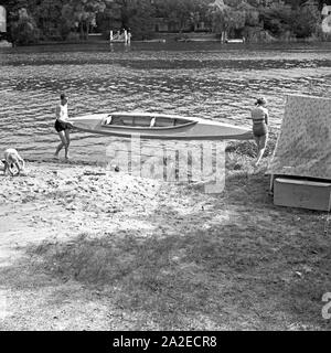 Ein Mann und eine Frau bringen ein Klepper Faltboot zu Wasser, Deutschland 1930er Jahre. Un uomo e una donna portando una piegatura Klepper barca in acqua, Germania 1930s. Foto Stock