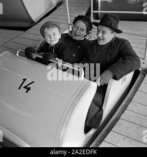 Ein kleiner Junge mit seinen Eltern in der Gondel eines Fahrgeschäfts auf dem Weihnachtsmarkt, Deutschland 1930er Jahre. Un ragazzino con i suoi genitori in una gondola di una fiera a guidare il mercato di natale, Germania 1930s. Foto Stock