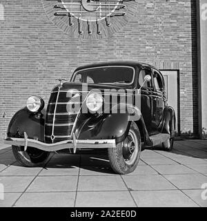 Ford V8 vor der Firmenzentrale der Ford Werke in Köln Niehl, Deutschland 1930er Jahre. Una Ford V8 nella parte anteriore del tedesco Ford sede a Colonia, Germania 1930s. Foto Stock