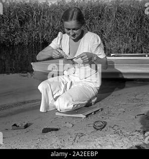 Eine junge Frau beim Zähneputzen am Ufer eines vede unter Verwendung von Nivea Produkten, Deutschland 1930s. Una giovane donna spazzolare i suoi denti con un prodotto della linea Nivea, Germania 1930s. Foto Stock