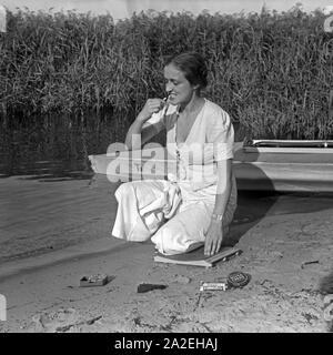 Eine junge Frau beim Zähneputzen am Ufer eines vede unter Verwendung von Nivea Produkten, Deutschland 1930s. Una giovane donna spazzolare i suoi denti con un prodotto della linea Nivea, Germania 1930s. Foto Stock