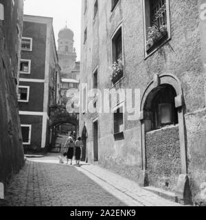 Zwei junge Frauen gehen mit dem Hund durch eine kleine Gasse in Passau auf Richtung Stephansdom, Deutschland 1930er Jahre. Due donne e il loro cane passeggiando attraverso un piccolo vicolo di Passau con la direzione per la cattedrale di Santo Stefano, Germania 1930s. Foto Stock