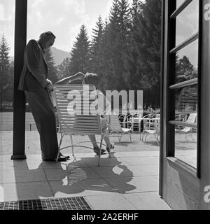 Eine Frau beim Sonnenbad auf der Terrasse am Kurhaus di Herrenalb im Schwarzwald unterhält sich mit ihrem Mann, Deutschland 1930er Jahre. Una donna che parla di suo marito mentre si prende il sole sulla terrazza della spa resort di Herrenalb nella Foresta Nera, Germania 1930s. Foto Stock