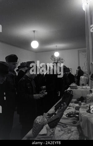 Besucher der Leipziger Frühjahrsmesse vor einem Stand mit Kunsthandwerk; Deutschland 1941. I visitatori della Leipziger Frühjahrsmesse davanti a un cavalletto con artwork; Germania 1941. Foto Stock