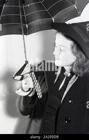 Ein Besucherin der Wiener Modewoche, im Haus der modo ' Palais Lobkowitz', bei einer Päsentation von Regenschirmen, Deutschland 1940er Jahre. Un visitatore della Vienna fashion week, nella casa di moda ' Palais Lobkowitz', a una presentazione di ombrelli, Germania 1940s. Foto Stock