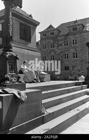 Junge Frauen genießen die Sonne vor dem Schillerdenkmal a Stoccarda, Deutschland 1930er Jahre. Giovani donne godendo il sole seduti di fronte al monumento a Schiller a Stoccarda in Germania 1930s. Foto Stock