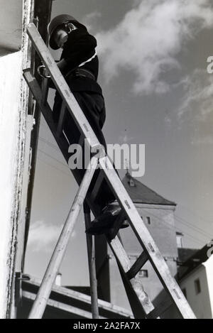 Ein Junge von der Kinderfeuerwehr erklettert bei einer Feuerwehrübung eine Leiter, Deutschland 1930er Jahre. Un ragazzo della junior vigili del fuoco è salire una scala a pioli durante un vigile del fuoco di formazione, Germania 1930s. Foto Stock