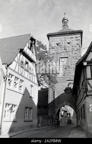 Ein Fahrradfahrer fährt durch das Sieberstor a Rothenburg ob der Tauber, Deutschland 1930er Jahre. Un ciclista è la guida attraverso il cancello Siebers / Sieberstor a Rothenburg ob der Tauber, Germania 1930s. Foto Stock