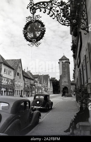 Zwei Schuljungen sitzen auf einer Bank vor zwei parkenden Autos, Rothenburg ob der Tauber, Deutschland 1930er Jahre. Due ragazzi della scuola seduta su una panchina di fronte a due posti auto, Rothenburg ob der Tauber, Germania 1930s. Foto Stock