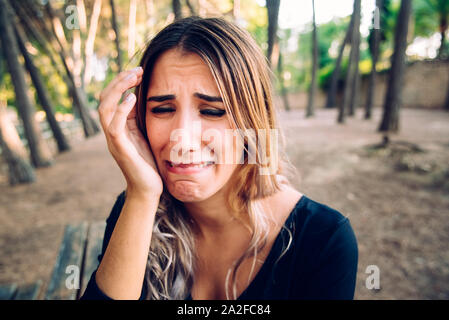 Bellissimo volto di donna piangendo nel disgusto come lei appoggia la testa sulla sua mano. Foto Stock