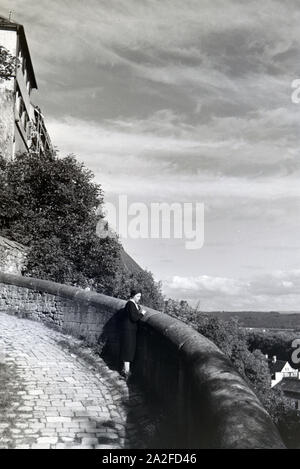 Eine junge Frau genießt den Ausblick vom Schloss Hohentübingen über die Altstadt Tübingens, Germania 1930er Jahre. Una giovane donna enyoing la vista panoramica dal castello di Hohentübingen oltre il quartiere storico di Tubinga, Germania 1930s. Foto Stock