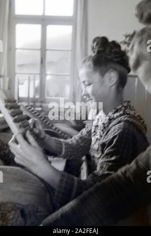 Eine Zigarrenrollerin in Marburger Tracht bei der Arbeit in einer Zigarrenfabrik bei Marburg, Deutschland 1930er Jahre. Una femmina di sigaro a rulli che indossa un abito di Marburg / costume di lavorare in un tessuto di sigaro vicino a Marburg, Germania 1930s. Foto Stock