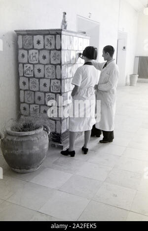 Zwei Schüler der Fachschule für Keramik in Höhr-Grenzhausen betrachten die individuell gestalteten Kacheln des Kachelofens im Flur der Schule, Deutschland 1930er Jahre. Due studenti del Collegio per la Ceramica di Höhr-Grenzhausen guardando il progettato individualmente le piastrelle della stufa in maiolica nel corridoio della scuola, Germania 1930s. Foto Stock