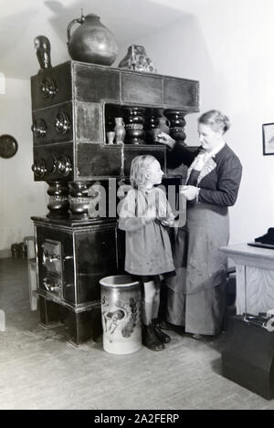 Eine Töpfermeisterin aus dem Kannenbäckerland zeigt einem kleinen Mädchen einen fertig gebrannten Tonkrug, Deutschland 1930er Jahre. Un Maestro vasaio sta mostrando un gres finito caraffa per una bambina, Germania 1930s. Foto Stock