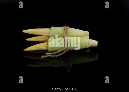 Giovani materie baby corn isolati su sfondo nero con una piccola riflessione Foto Stock