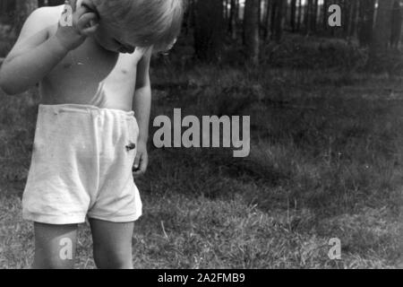 Kleiner Junge beobachtet einen Maikäfer, Deutschland 1930er Jahre. Little Boy guardando un maggio maggiolino, Germania 1930s. Foto Stock