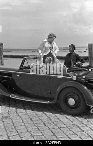 Eine Frau unterhält sich mit einem Parkwächter einer Garage in Norddeich, Deutschland 1930er Jahre. Una donna a parlare con un operatore di parcheggio di un garage di Norddeich, Germania 1930s. Foto Stock