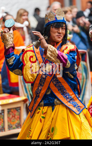 Bumthang, Bhutan, 06 Nov 2011: Performer dancing in colorati costumi al festival a Jakar Dzong tenendo cerimoniale campana a mano. Foto Stock